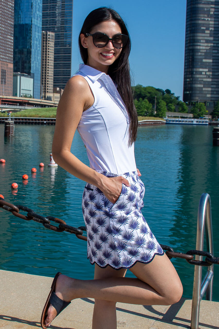 Woman wearing navy and white stretch cotton golf skort with a white sleeveless polo