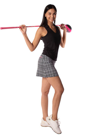 Woman wearing black and white plaid golf skort with a matching black sleeveless polo