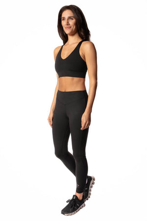Woman wearing matching yoga outfit with black sports bra and martini leggings