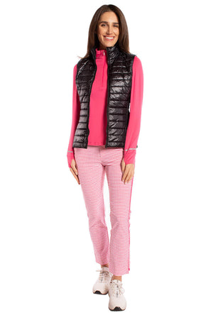 Pink women's golf outfit with matching plaid pants and black tech vest
