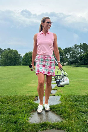 Female golf instructor in cute pink golf outfit by Golftini going to practice her game at the driving range