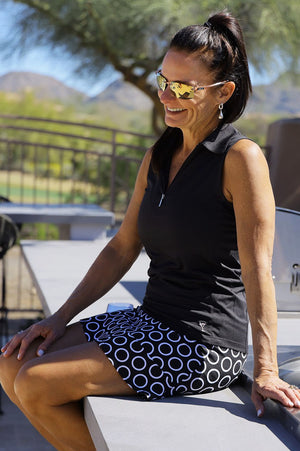 Lady golfer wearing cute black and white skort and black sleeveless polo outside her country club in Arizona