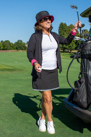 Lady golfer with matching black white and pink outfit from designer golf brand on the course